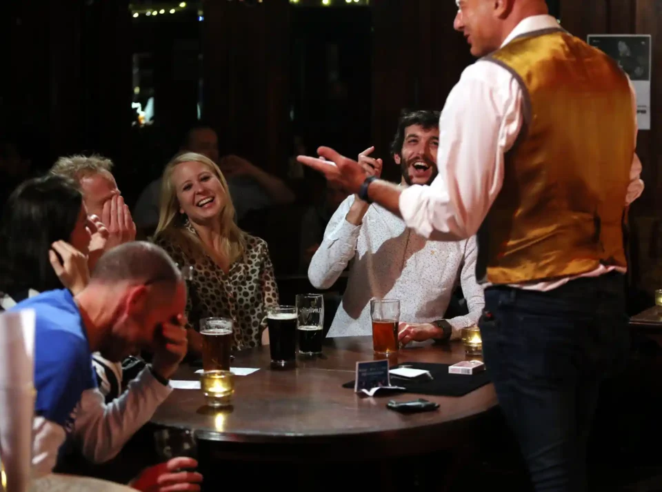 Close-up magician Roberto Forzoni bamboozles a crowd that sat in front of him- all four hold their heads in their hands in disbelief