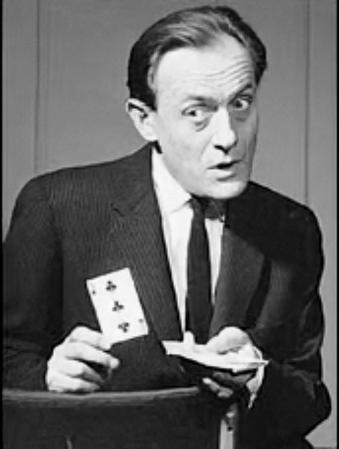 Chan Canasta holding a playing card, the four of clubs, with a startled expression